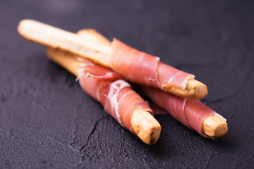 Traditional italian bread sticks grissini with prosciutto ham