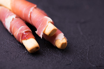 Traditional italian bread sticks grissini with prosciutto ham