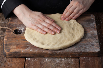 Chef kneading dough, Making dough by female hands at bakery on a black background