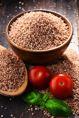 Bowl of uncooked spelt on wooden table