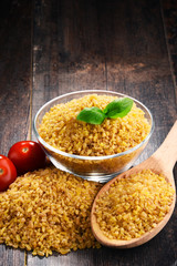 Bowl of uncooked bulgur on wooden table