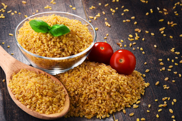 Bowl of uncooked bulgur on wooden table