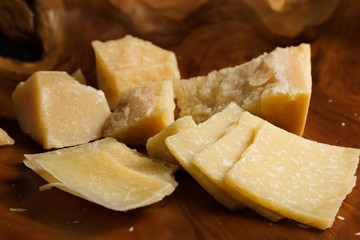 Parmesan cheese on a wooden board. Pieces of cheese close-up.