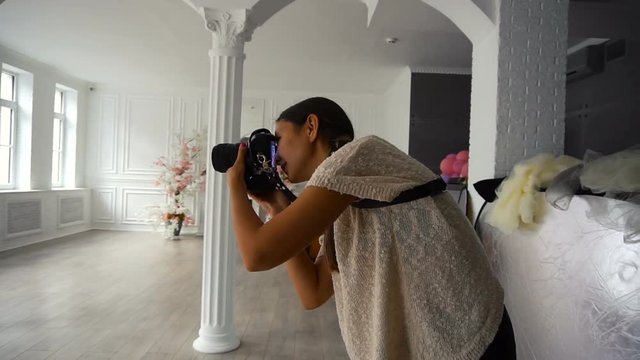 Young charming Woman photographer taking photos with dslr camera indoors with grunge interior room