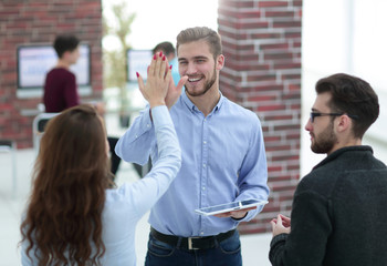Photo of happy young business people holding a tablet and giving