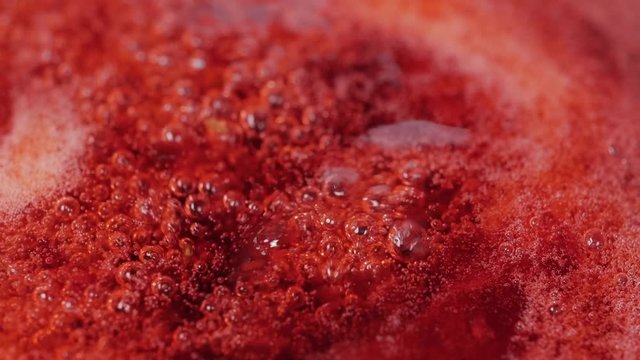 Close up of red cranberries boiling process in the boiler for jam. Macro shot.