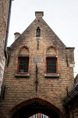 Fototapeta na wymiar A red brick building with a gable on top an arch in brugge, Belgium