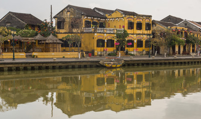Obraz premium typical mustard yellow buildings with tile roofs reflected on the river in old town of Hoi An, Vietnam 