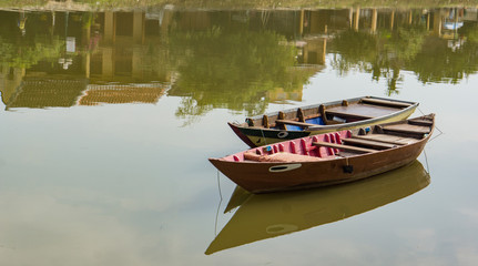 Obraz premium two paddle or row boats anchored in river reflecting riverside building on old Hoi An town in Vietnam 