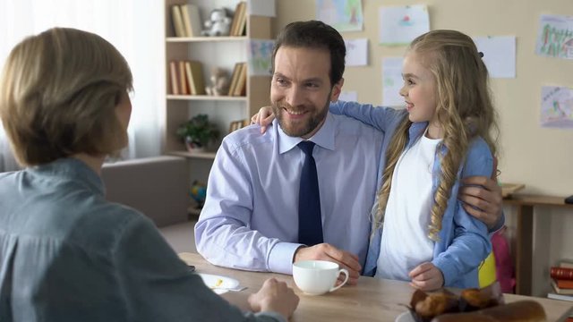 Beautiful female kid kissing loving father at kitchen, family conversation