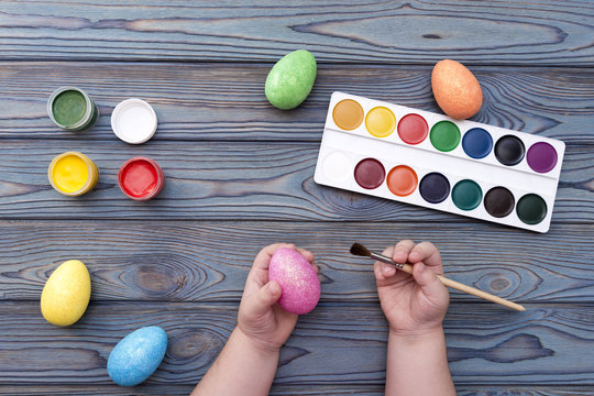 Easter egg and a brush in the hands of a child. coloring eggs on a holiday.