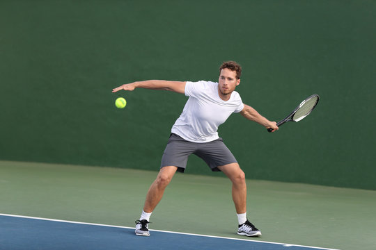 Professional tennis player athlete man hitting forehand ball on hard court playing tennis match. Sport game fitness lifestyle person living an active summer lifestyle.