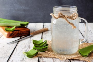 Healthy Aloe vera juice in a mason jar glass. Still life, side view on white wood.