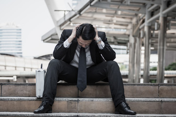 Tired or stressed businessman sitting on the walkway in the city after his work. Image of Stressed businessman concept.