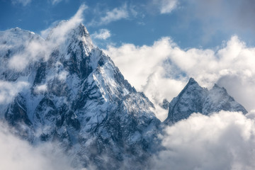 Majestical scene with mountains with snowy peaks in clouds in Nepal. Landscape with beautiful high rocks and dramatic cloudy sky in sunny bright day. Nature background. Vintage. Amazing Himalayas