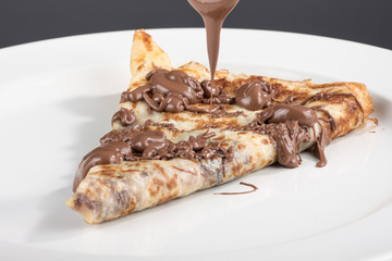 gefaltete Crepe gefüllt mit Schokolade Schokoladenüberzug wird verteilt auf weißen Teller