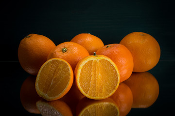 frische Orangen nebeneinander mit aufgeschnittener Orange dunkler Hintergrund