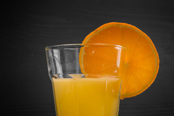 Orange am Glas mit Orangensaft mitte grauer Hintergrund