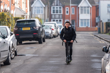 Boy on electrical scooter driving to British school in UK