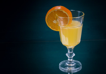 Orangescheibe am Glas mit Orangensaft rechts