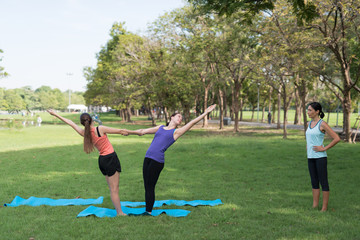 Family practicing yoga in the park outdoor. Concept of healthy lifestyle and relaxation..