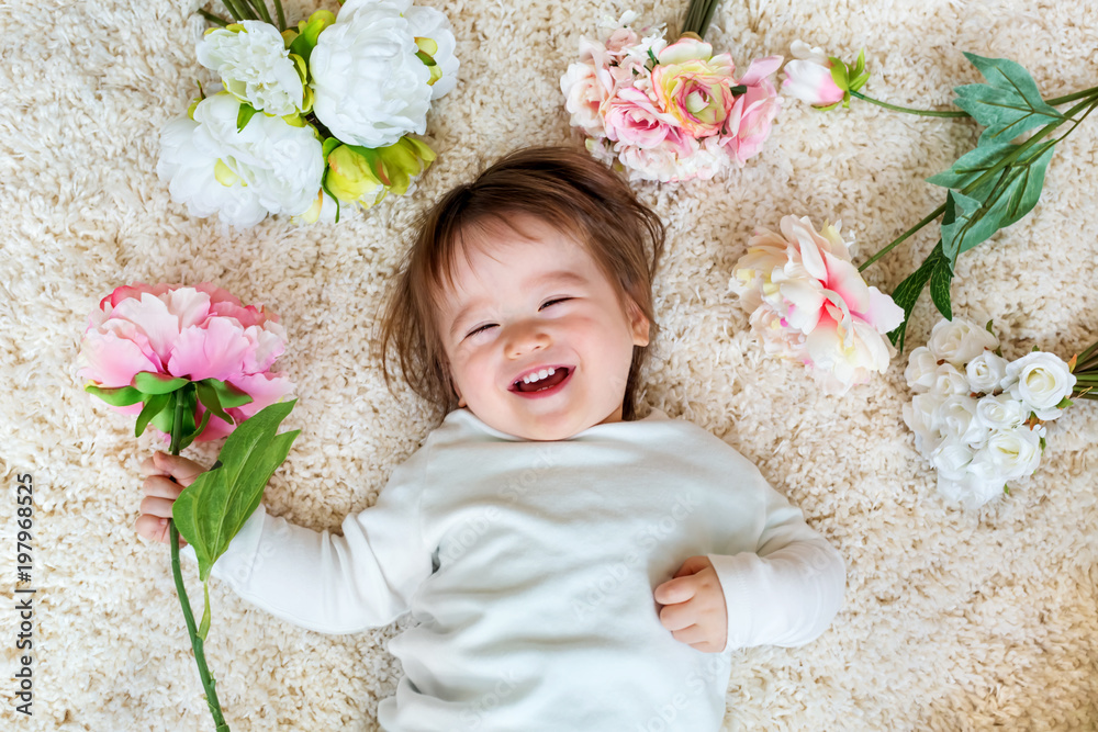 Sticker Happy toddler boy with spring flowers on a white carpet