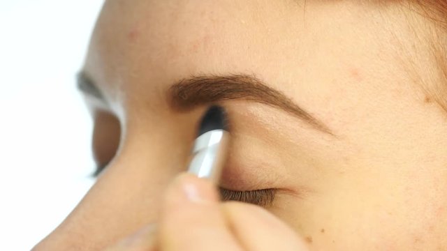 Close-up make-up artist hand, applying eyeshadow to woman's eye using brush. 4K