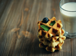 Waffles and glass with milk. Morning breakfast on wooden background.