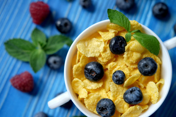 Healthy eating, food and diet concept - Cornflakes with berries raspberries and blueberries on blue wooden background. Top view.