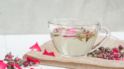 A cup of tea pink rose on a white wooden table.
