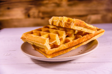 Ceramic plate with belgian waffles on wooden table