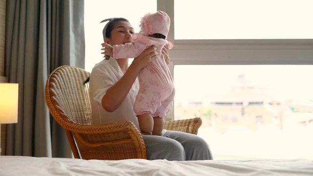 happy asian family mother playing and hug with newborn baby in the bed room