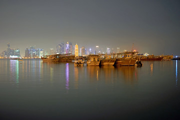 Fototapeta na wymiar Traditional Dhows in front of nightly Doha Skyline