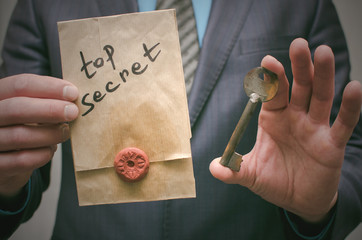 Top secret concept. Top secret documents or message and a decryption key in businessman hands. The...