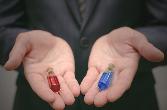 Blue And Red Pill Essential Liquid In Business Man Hands. Choosing Of Right Pill. Steroid Or Drug Presentation. Medication For All Diseases Concept. Pharmacological Or Pharmaceutical Business.