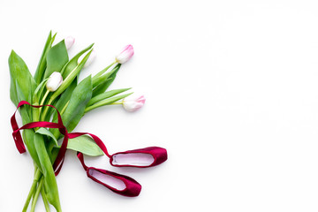 Ballet shoes near delicate flowers on white background top view copy space