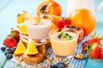 Orange persimmon blueberry smoothie with granola  and fruits. Selective focus. Copy space