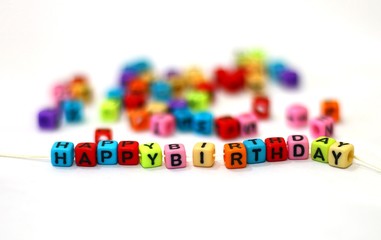happy birthday text cube on white with blur background