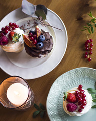 Homemade cupcakes with fresh berries in plates on wooden festive table