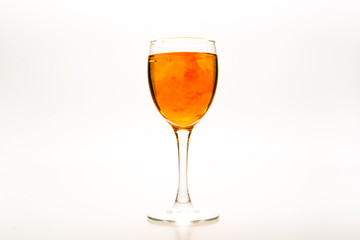 Orange food coloring diffuse in water inside wine glass with empty copy-space area for slogan or advertising text message, over isolated white background.