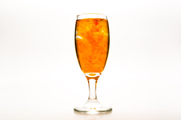 Orange food coloring diffuse in water inside wine glass with empty copy-space area for slogan or advertising text message, over isolated white background.
