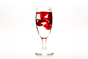 Red food coloring diffuse in water inside wine glass with empty copy-space area for slogan or...