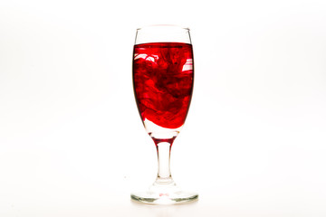 Red food coloring diffuse in water inside wine glass with empty copy-space area for slogan or advertising text message, over isolated white background.