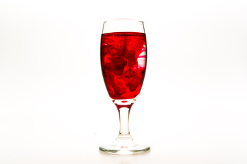 Red food coloring diffuse in water inside wine glass with empty copy-space area for slogan or advertising text message, over isolated white background.