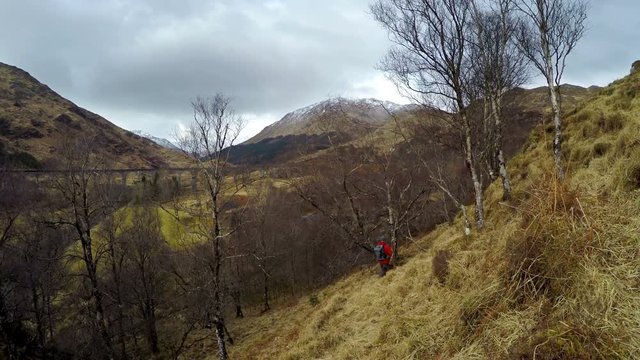 4K footage of Hiking, walk with backpack, active lifestyle concept image. Man traveler walks neaar famous Glenfinnan viadukt in Scotland