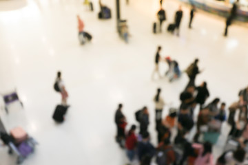 blurred image of crowd of travelling people or passenger walking with a luggage from flight in the international airport terminal with beautiful bokeh from the light,advertise & traveling concept.