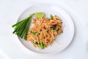 Pad Thai, stir-fried rice noodles with shrimp in white plate with slide lemon and green vegetable. The one of Thailand's national main dish. the popular food in Thailand. Thai Fried Noodles