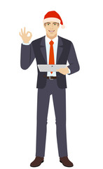 OK! Businessman in Santa hat showing a okay hand sign and holding digital tablet PC