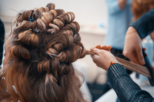 The hairdresser does hair extensions to a young girl