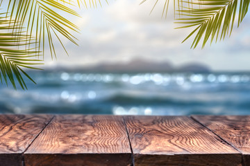 Beach blurred background with palm leaves background with vintage old wood table